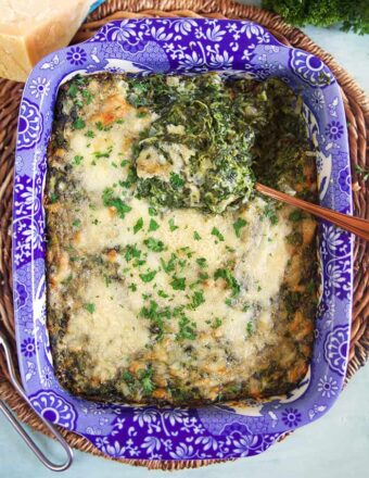 overhead shot of creamed spinach gratin in a blue and white baking dish.