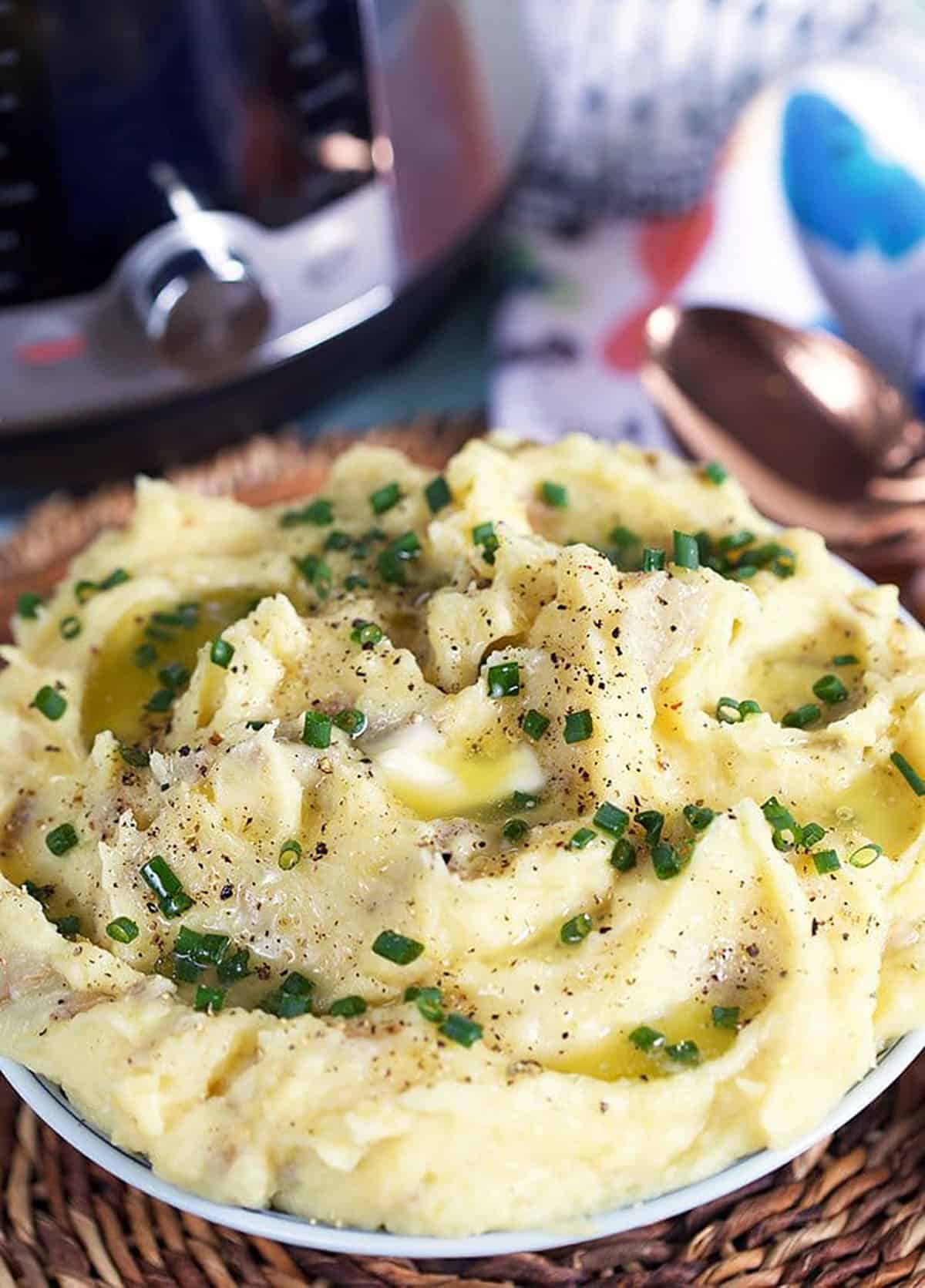 Mashed potatoes in a bowl with an instant pot in the background.