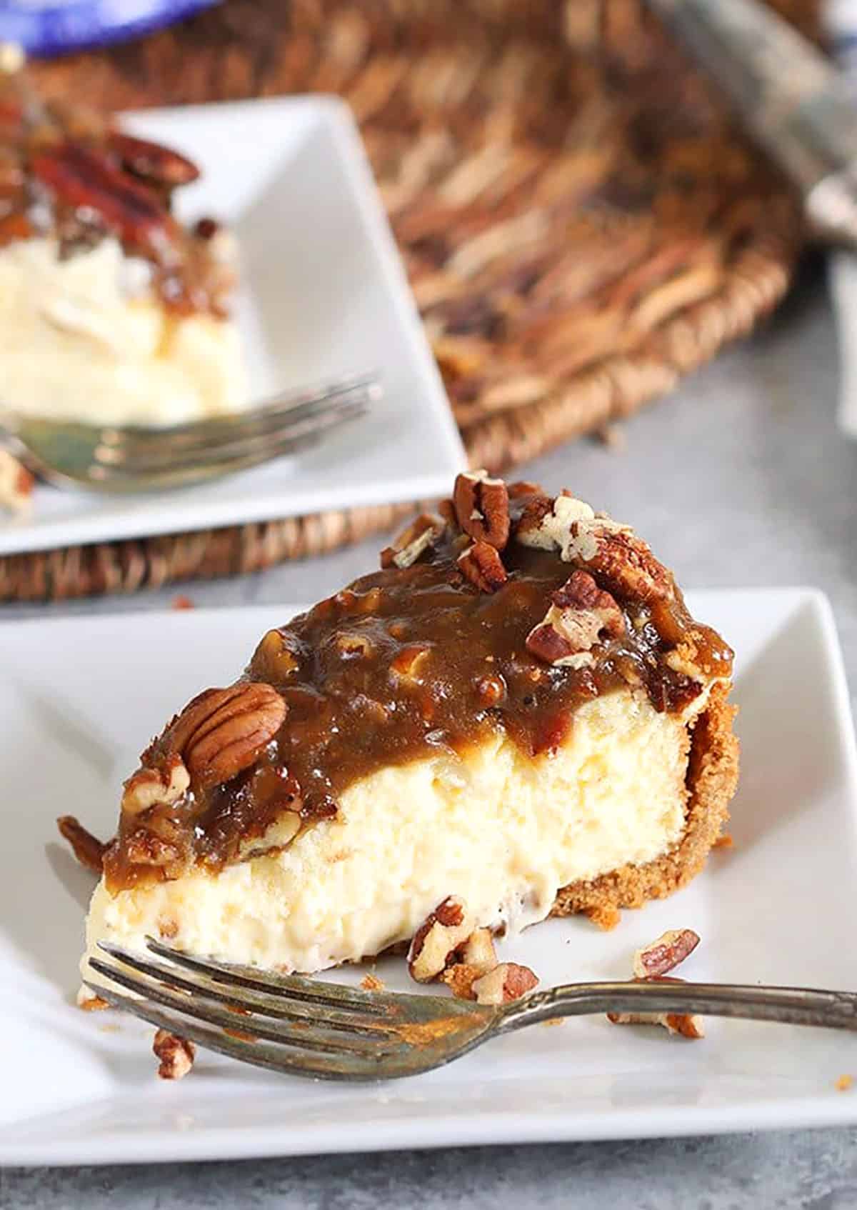 Pecan Pie cheesecake slice on a white square plate with a fork.