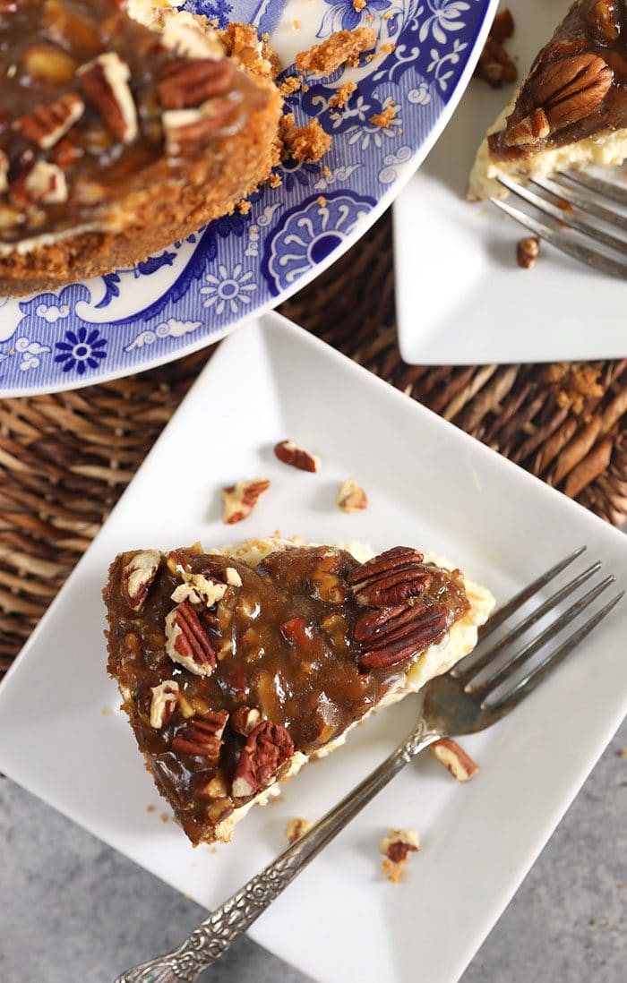 Slice of pecan pie cheesecake on a white square plate with a silver fork.