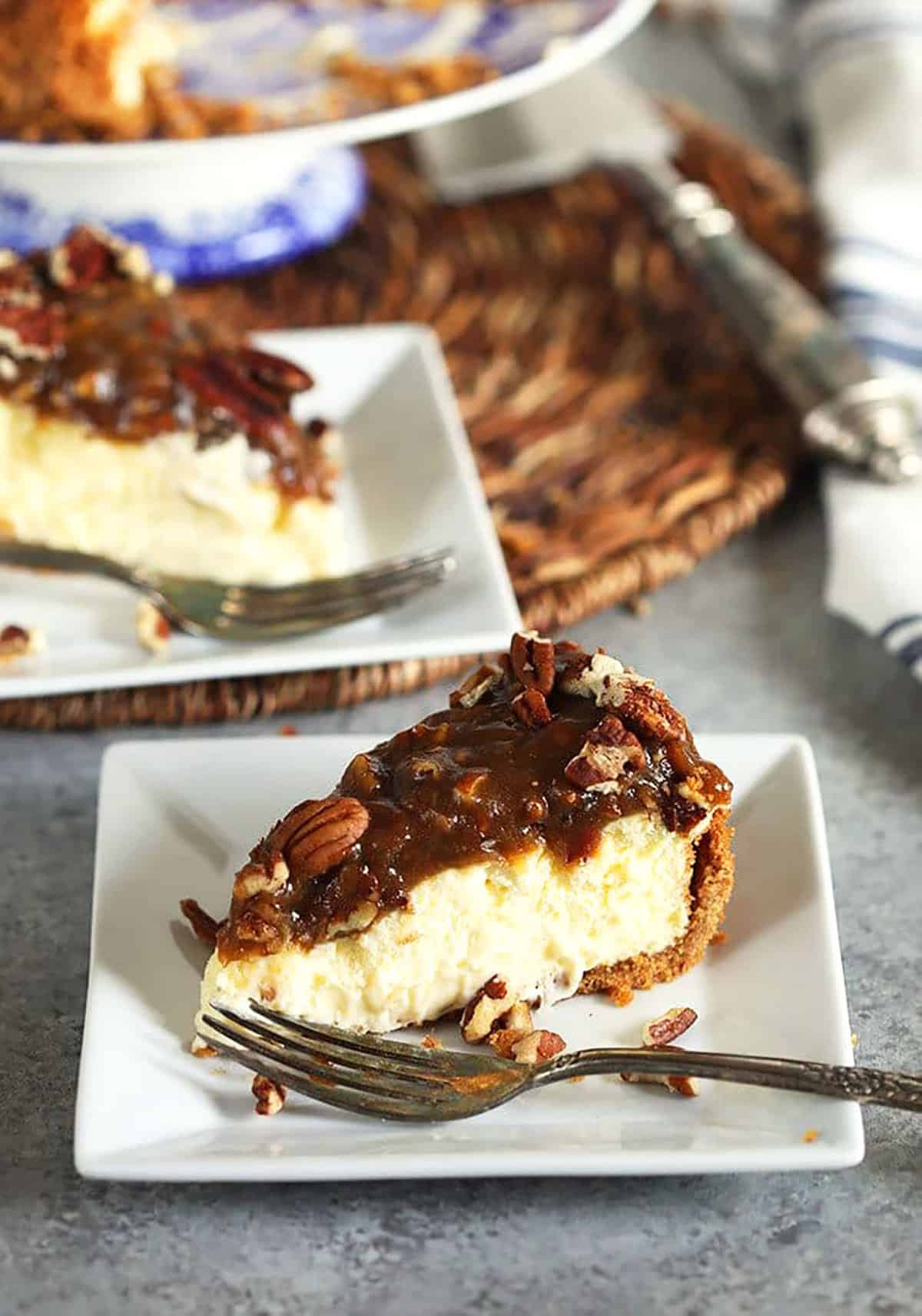 Slice of pecan pie cheesecake on a white square plate.