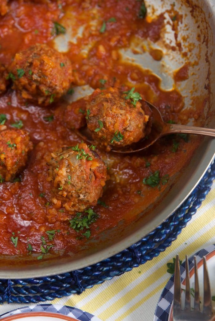 Porcupine meatballs in a skillet with a silver serving spoon.