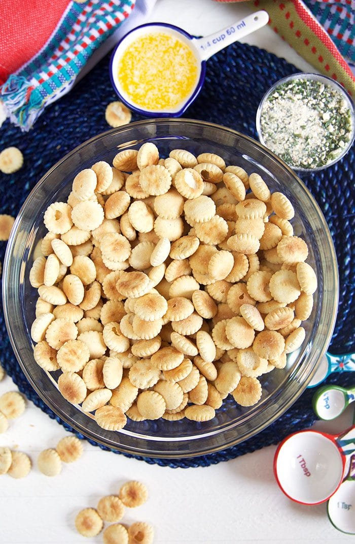 Overhead shot of oyster crackers in a glass bowl with butter and ranch seasoning next to it. 