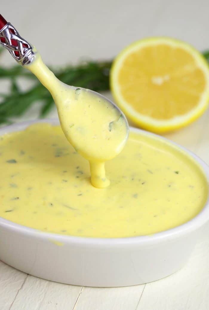 Bearnaise sauce in a white dish with a spoon.