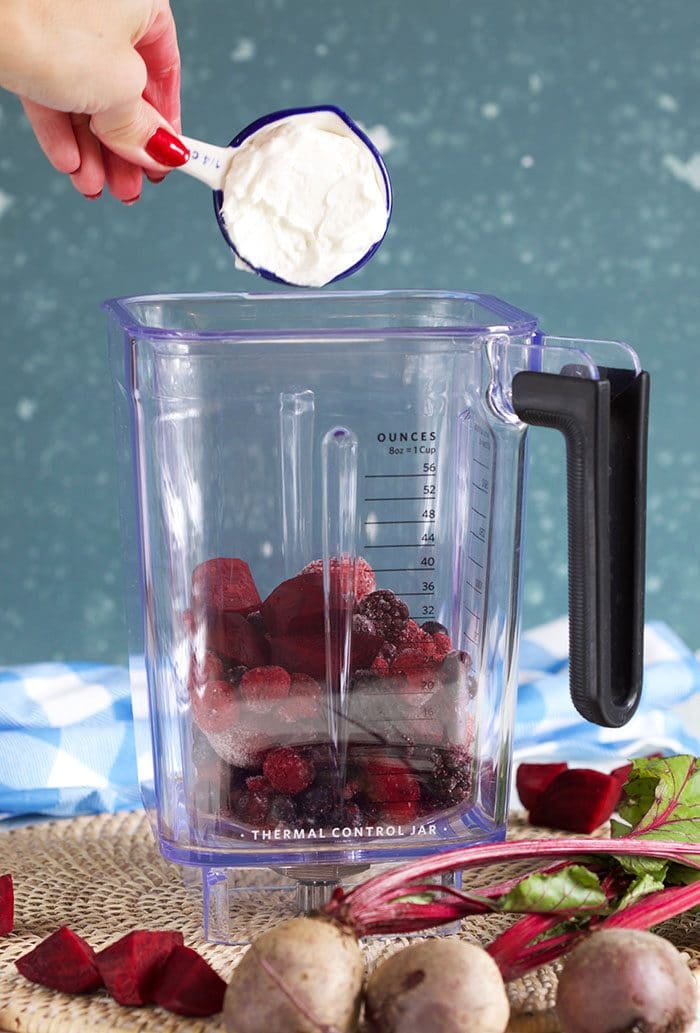 yogurt being added to blender pitcher for berry beet smoothie.