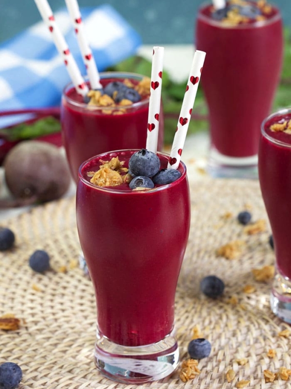 Berry Beet Smoothie in a small pilsner style glass with a paper straw with hearts on it.