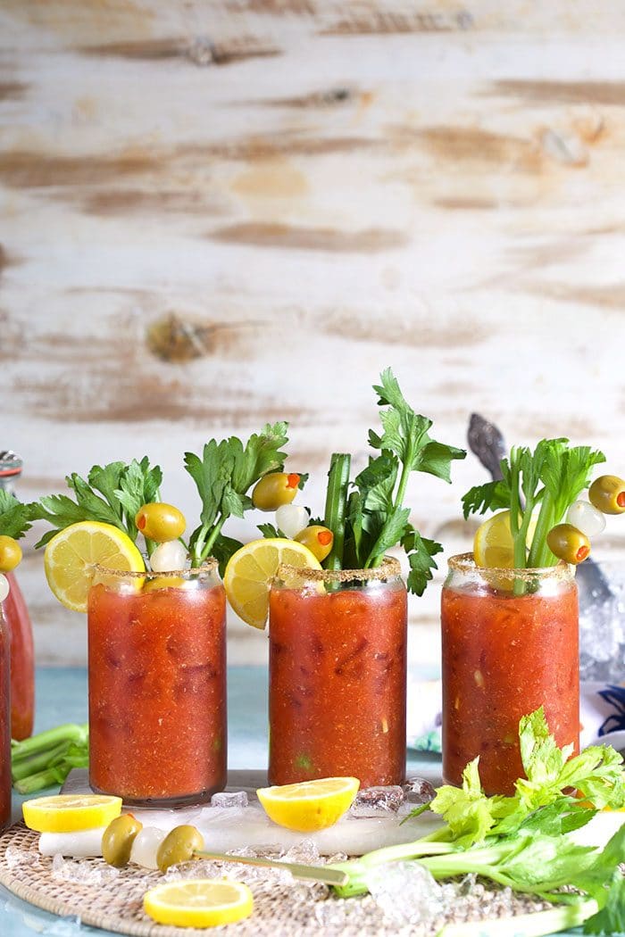 Bloody Mary cocktails lined up on a wicker placemat.