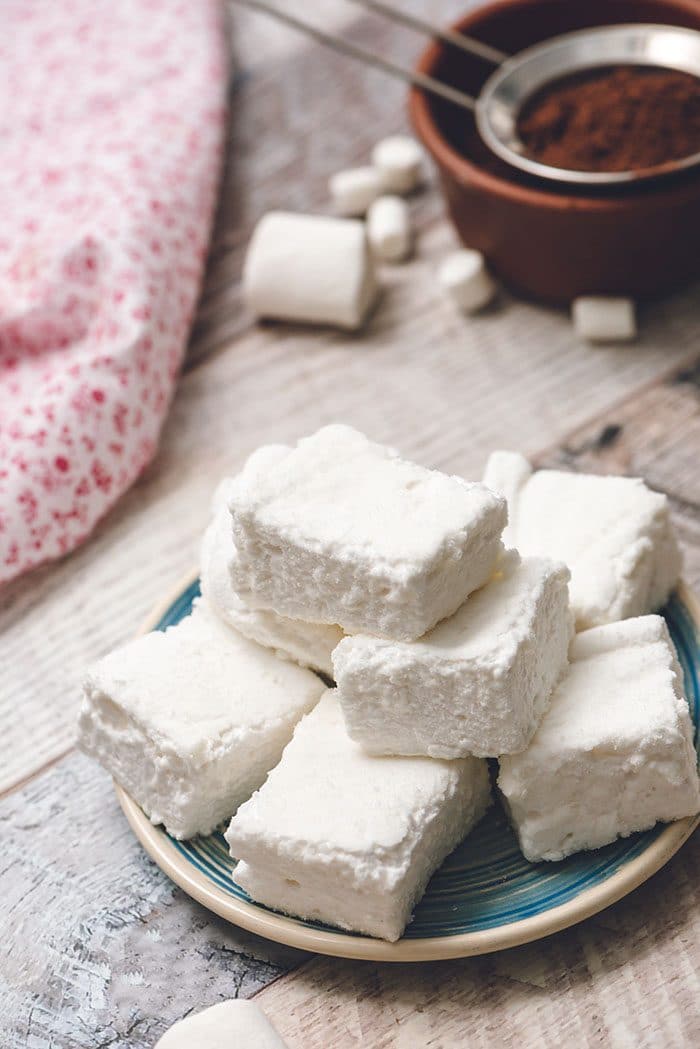 A plate of homemade marshmallows on a wood background.