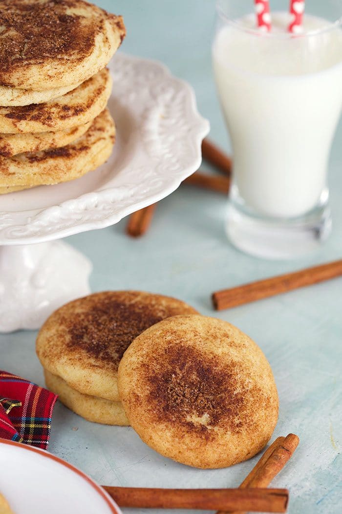 Snickerdoodle cookies with a glass of milk and a cinnamon stick.