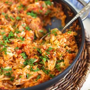 Stuffed cabbage casserole in a skillet with a spoon.