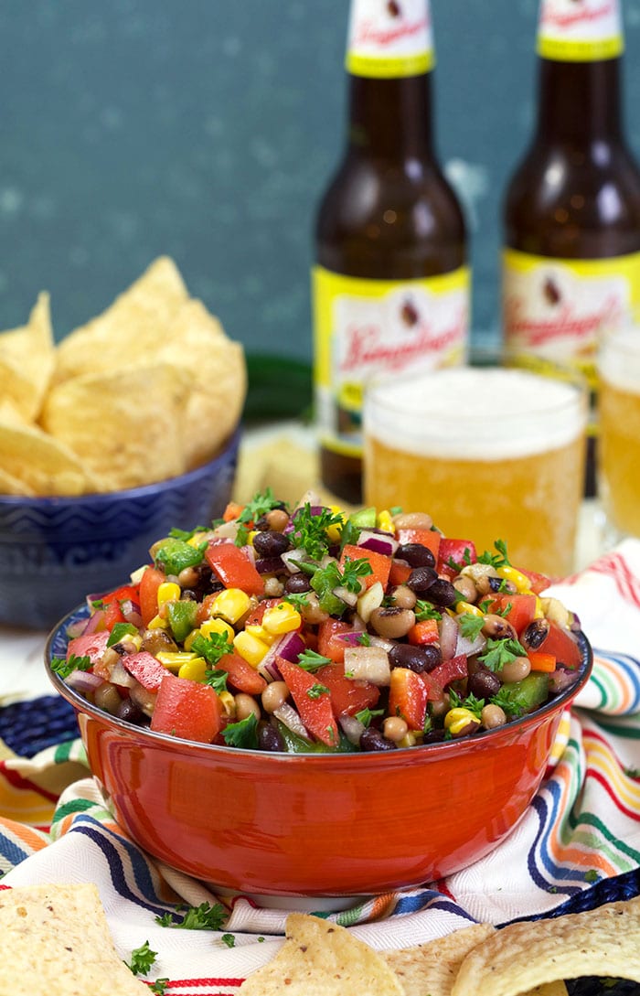 Texas caviar in a red bowl with beer in the background.