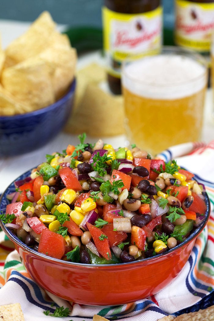Cowboy Caviar in a red bowl with a beer in the background.