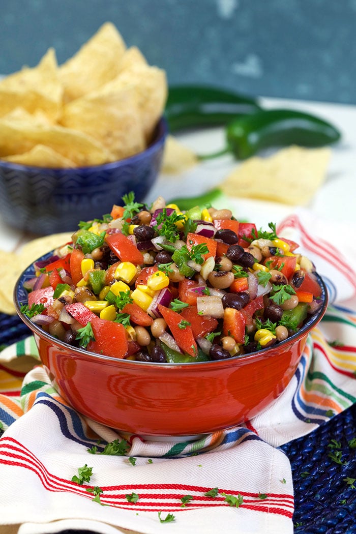 Texas caviar in a red bowl with jalapeños in the background.