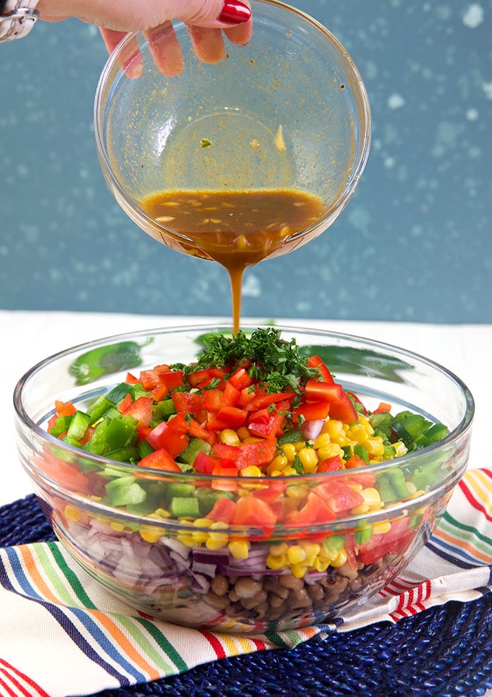 Dressing being poured over Texas caviar ingredients in a bowl.