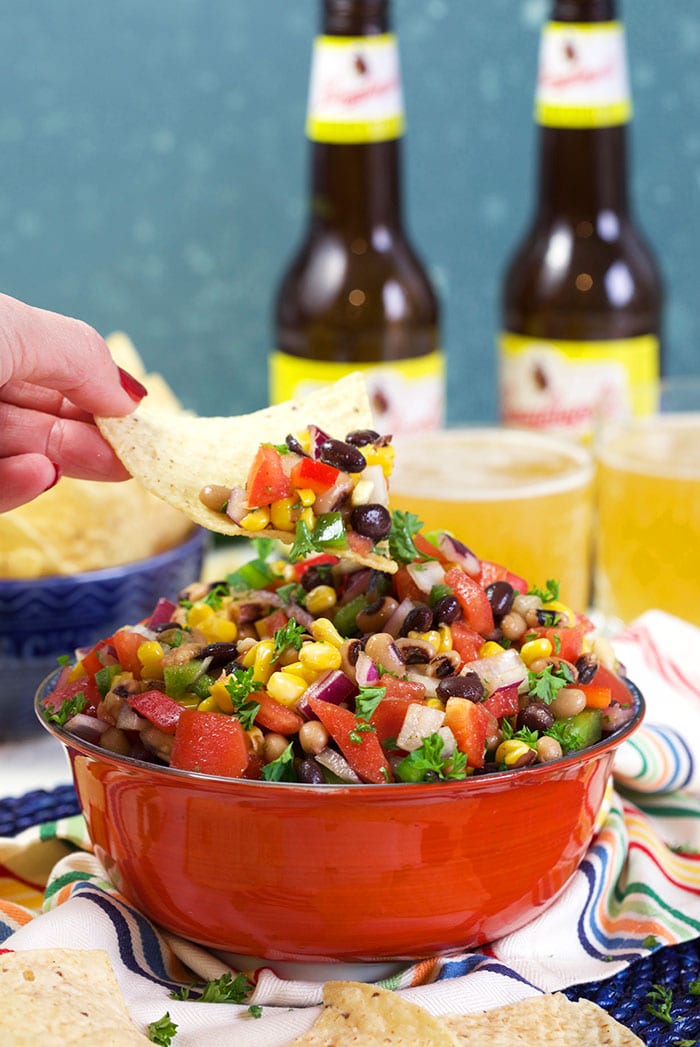 Cowboy Caviar in a red bowl with a chip dipping into it.
