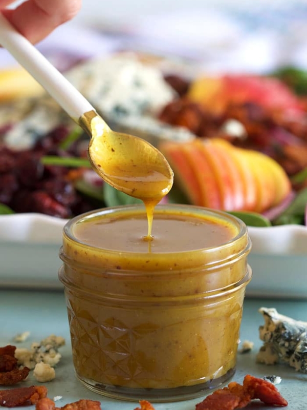 Hot Bacon Dressing in a glass jar with a spoon.