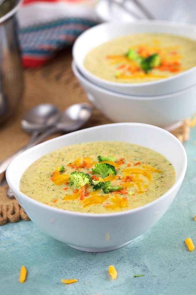 Broccoli Cheddar Soup in white bowls on a blue background.