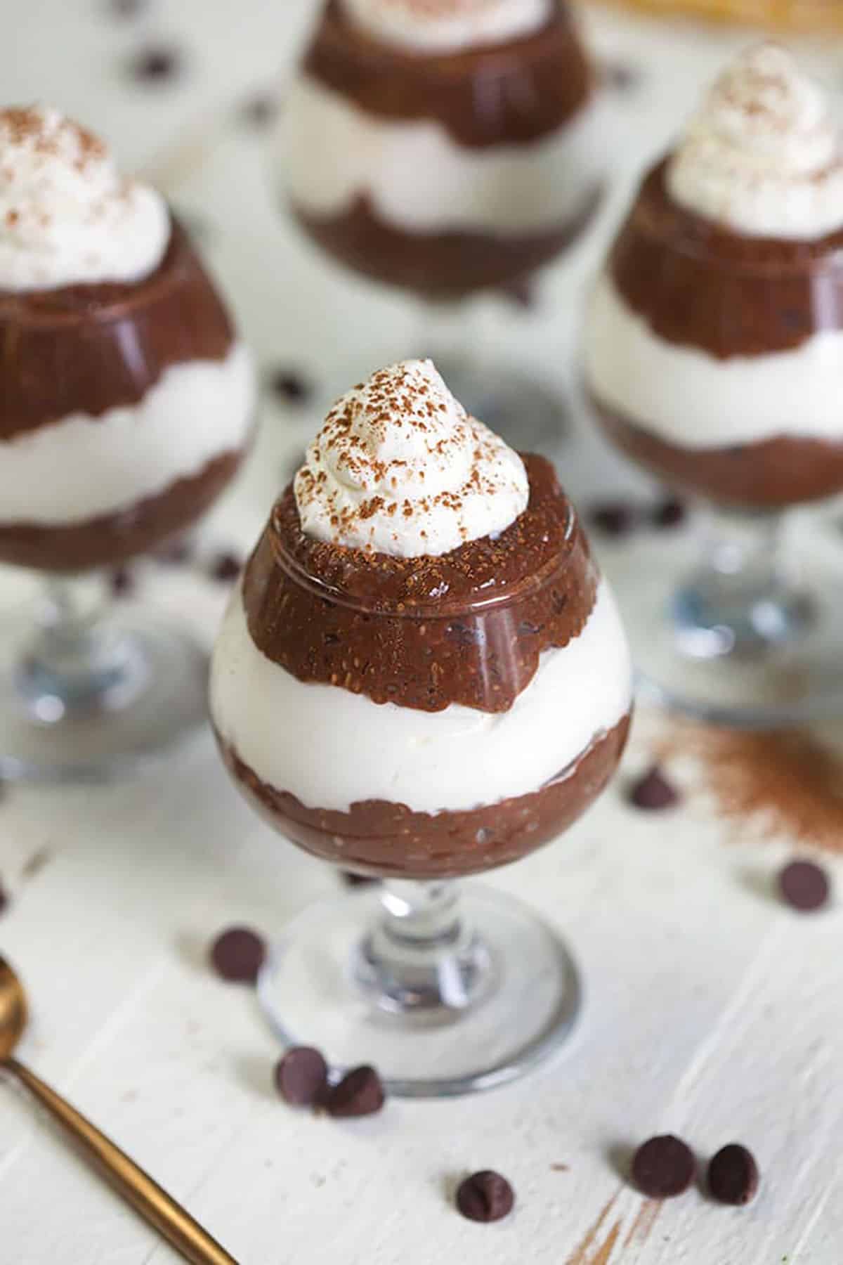 Chocolate Chia Pudding parfaits in mini wine glassed on a white background.