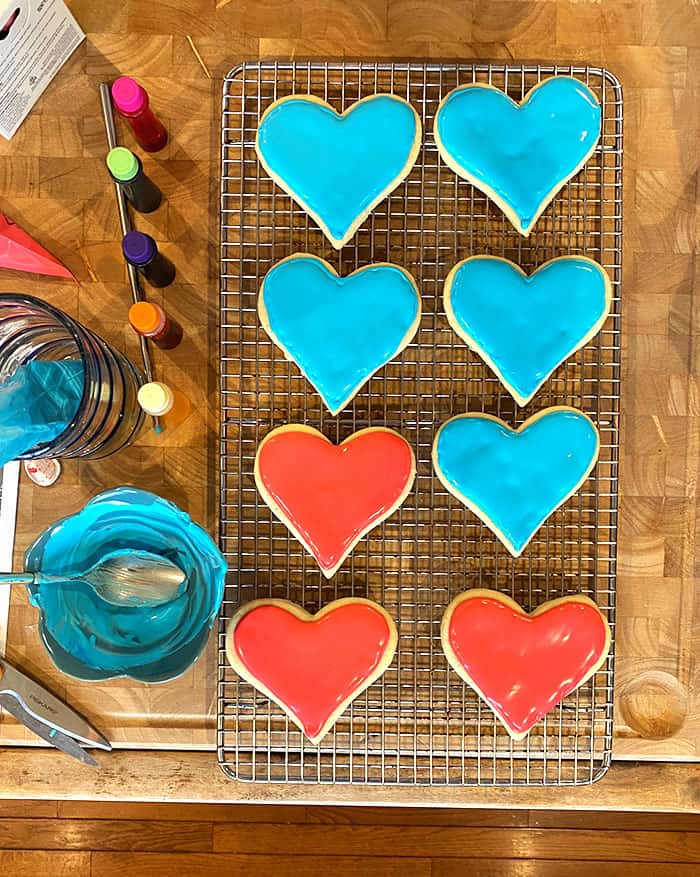 Overhead shot of heart cookies being decorated with royal frosting.