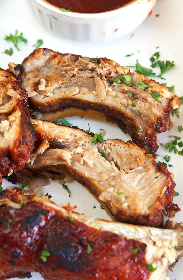 Close up of cut bbq ribs on a white platter.