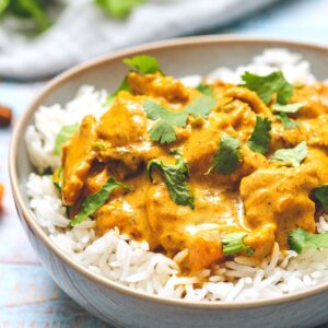 Butter Chicken in a bowl of rice with cilantro on top.