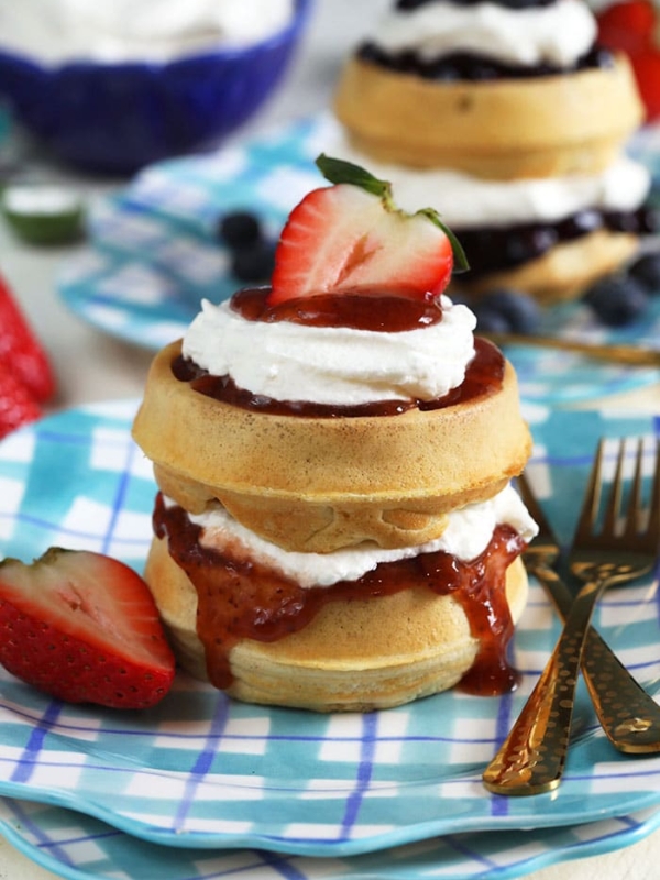 strawberry waffle cake with a bowl of whipped cream.