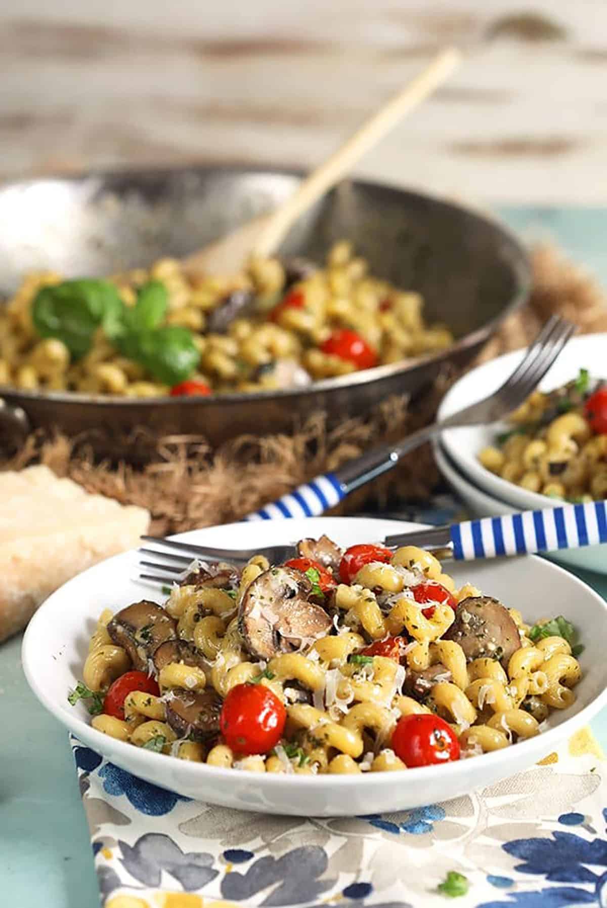 Pesto Cavatappi being served from a skillet into a white bowl.