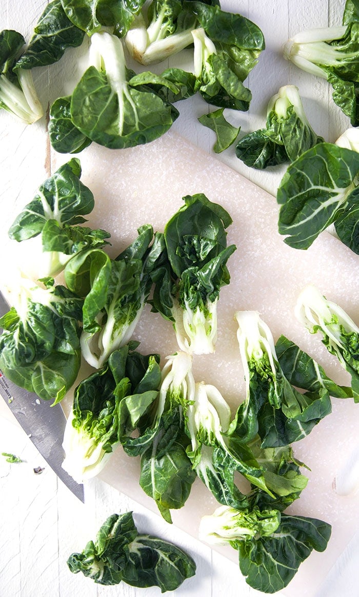 Bok Choy is spread out on a white surface.