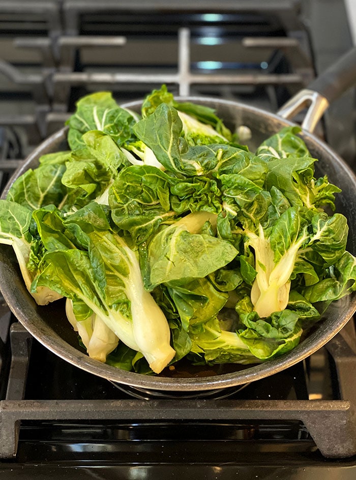 Bok Choy is in a skillet, ready to be cooked.