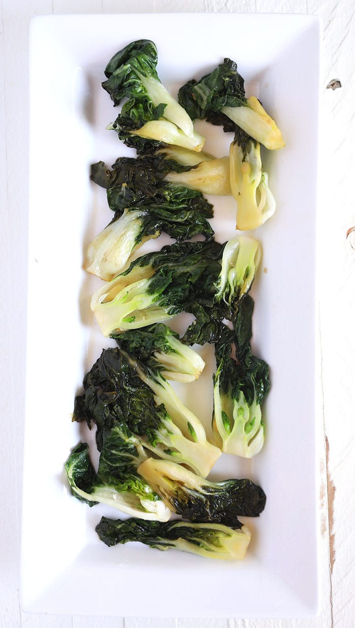 Cooked Bok Choy is presents on a white serving plate.