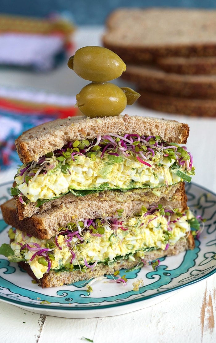 Egg Salad sandwich with olives on top.