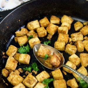 Crispy tofu is in a large black skillet.