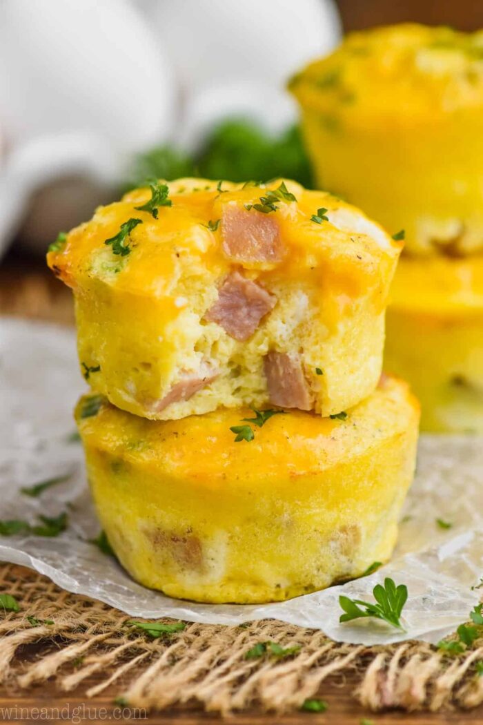 Ham and cheese egg muffins stacked on a piece of parchment.
