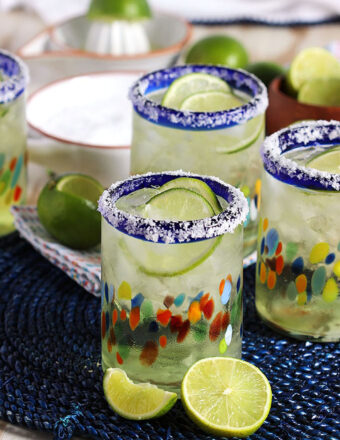 Margaritas in a festive glass with a sliced lime in front of it.