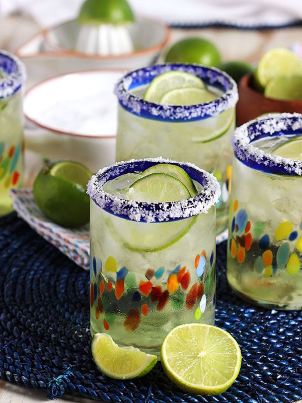 Margaritas in a festive glass with a sliced lime in front of it.