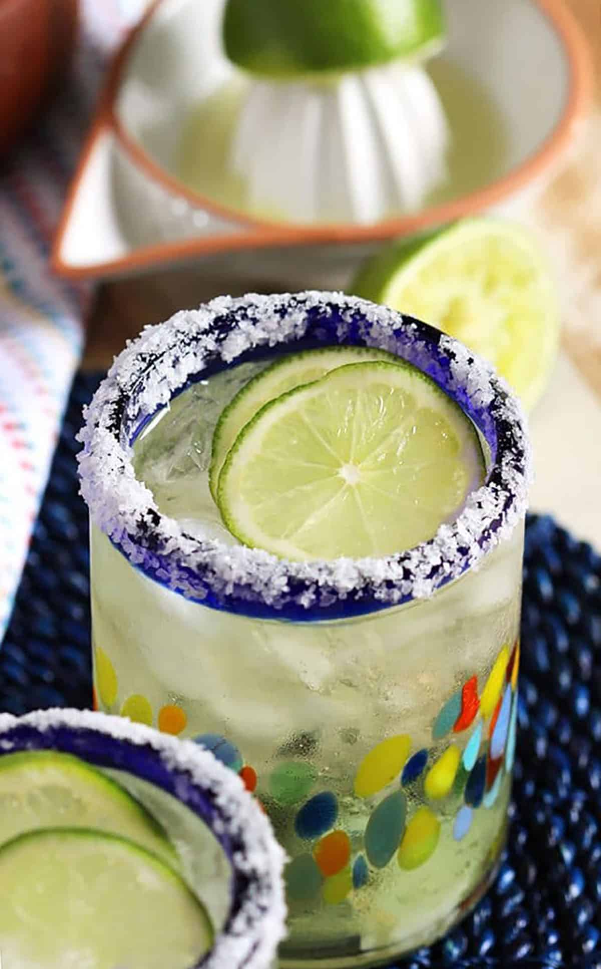margarita in a glass with lime slices on top and the rim coated with salt.