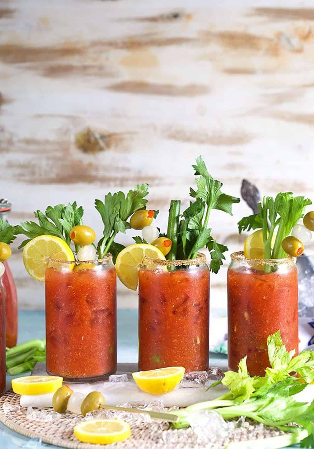 Bloody Mary cocktails lined up on a wicker placemat.