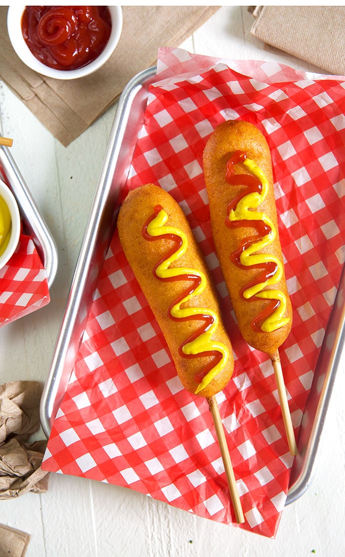 Overhead shot of corn dogs with ketchup and mustard on them.
