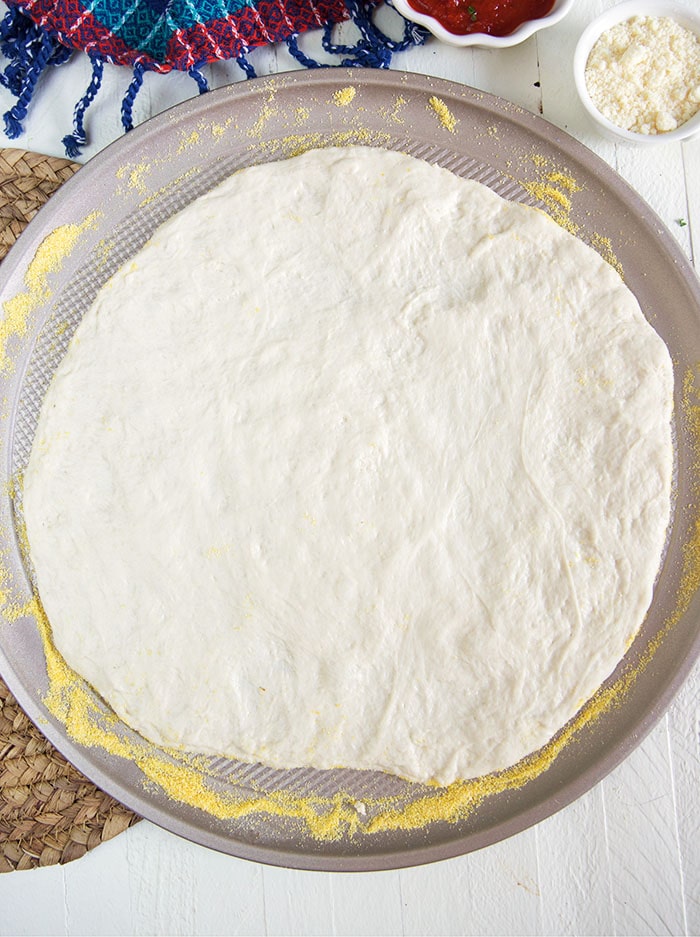 Pizza dough rolled out onto a pizza pan.