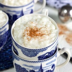 Creamy rice pudding in a blue and white coffee cup with cinnamon on top.