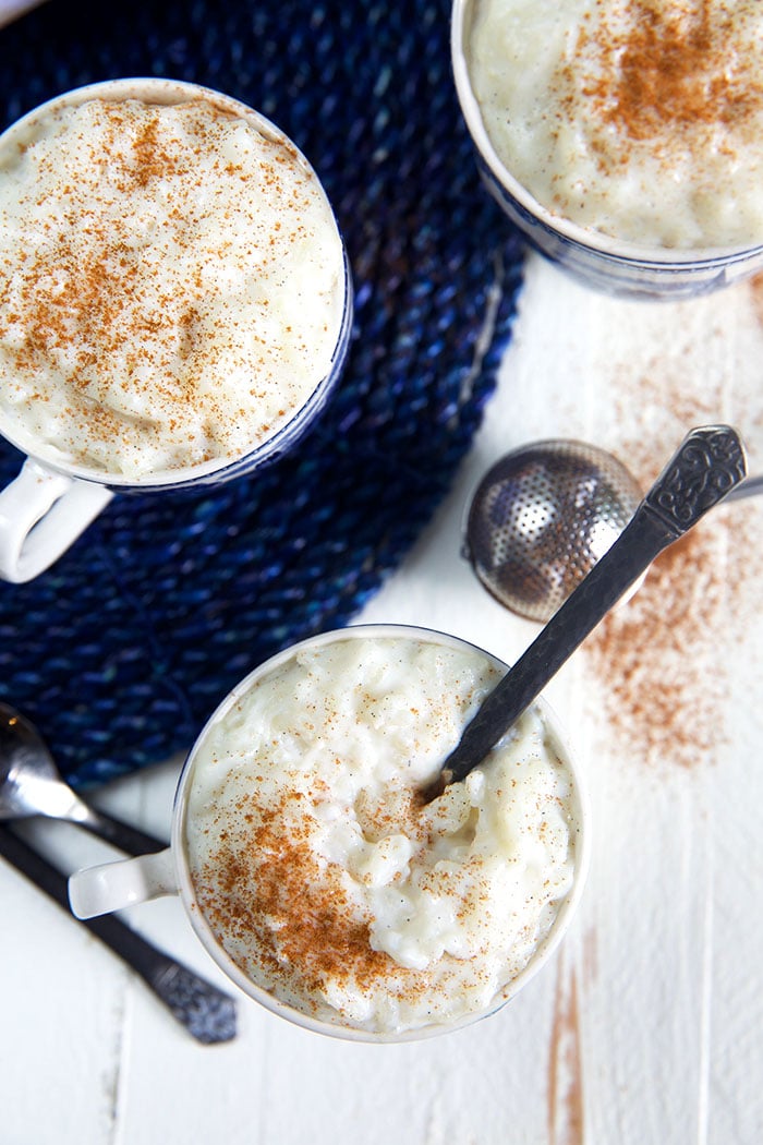 Overhead shot of rice pudding in a mug on a blue wicker placemat.