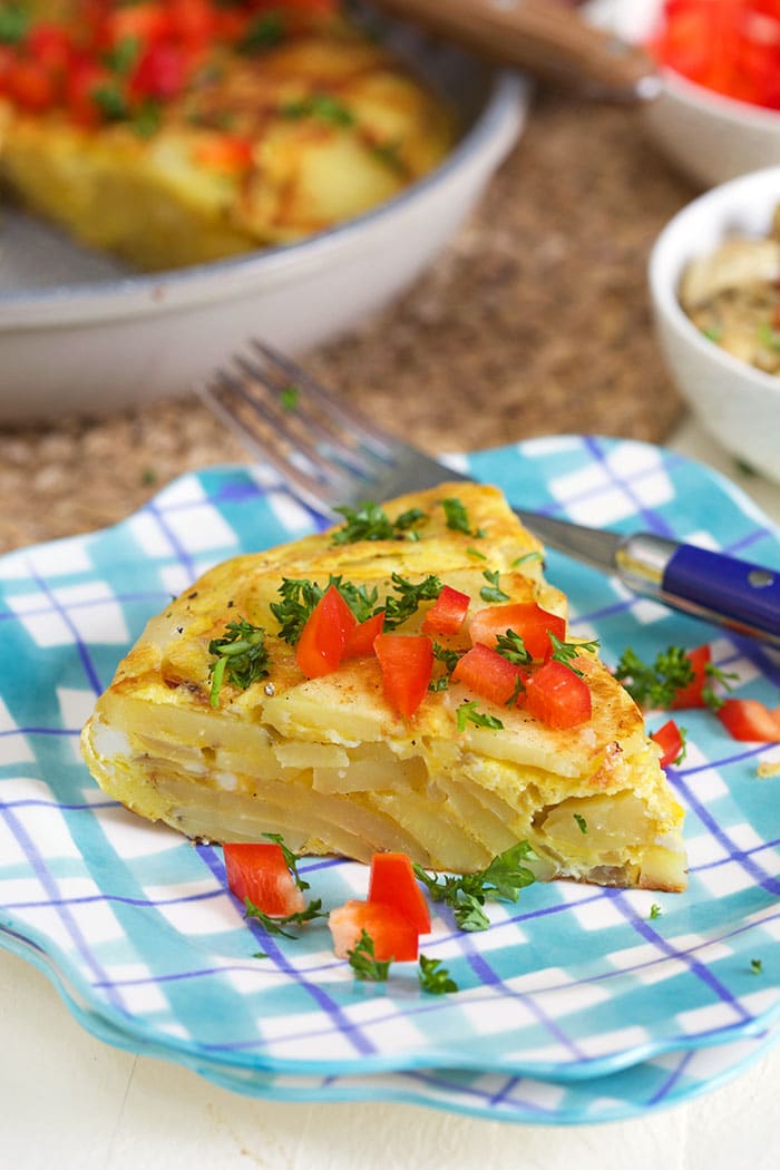 Spanish Tortilla slice on a plaid plate with bell pepper on top.