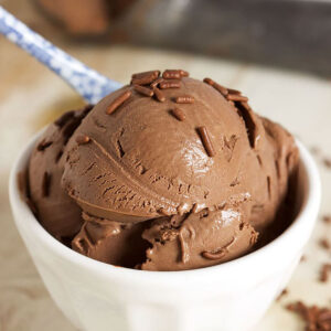 Chocolate Ice Cream in a white bowl with chocolate sprinkles and a blue and white spoon.