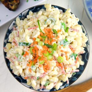 Overhead shot of macaroni salad in a blue bowl with a wooden spoon.
