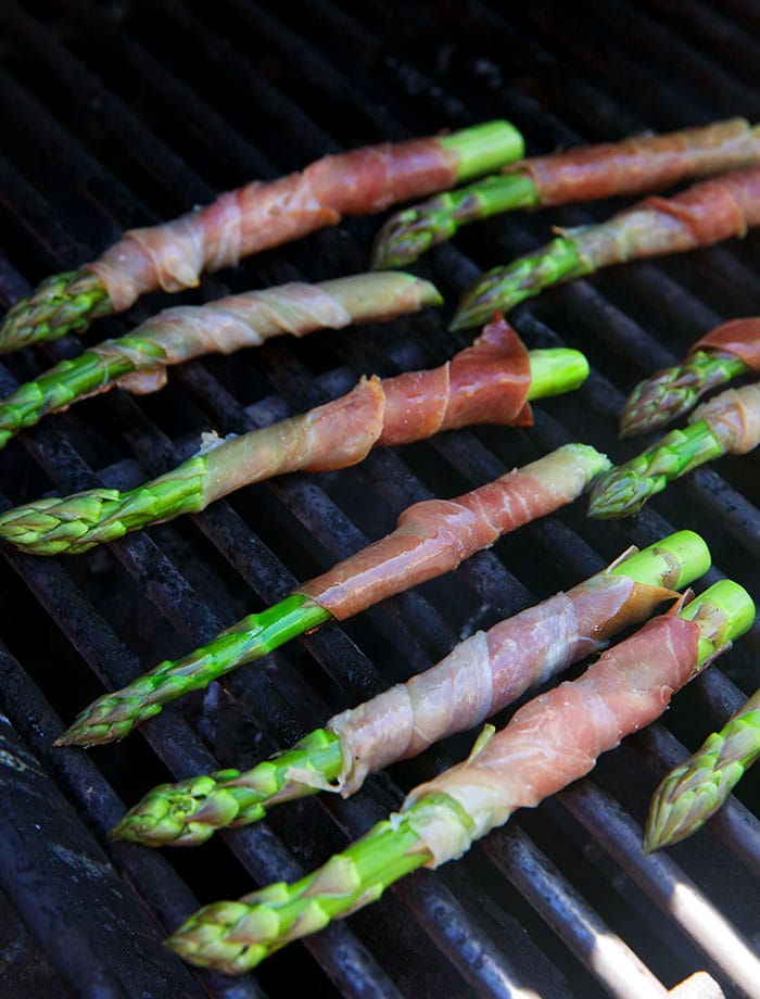 Prosciutto wrapped asparagus on a grill.