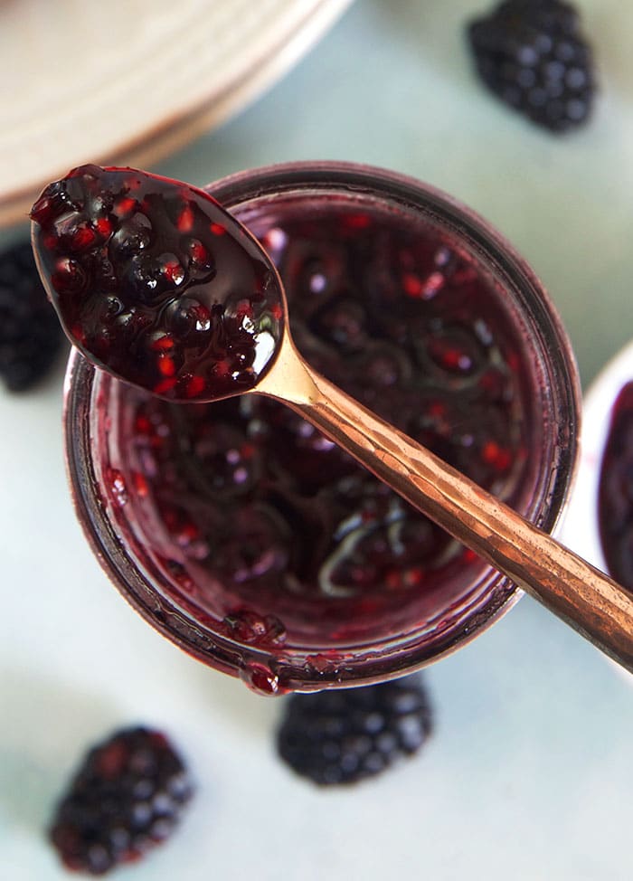 A spoon full of jam is placed on a jam jar.