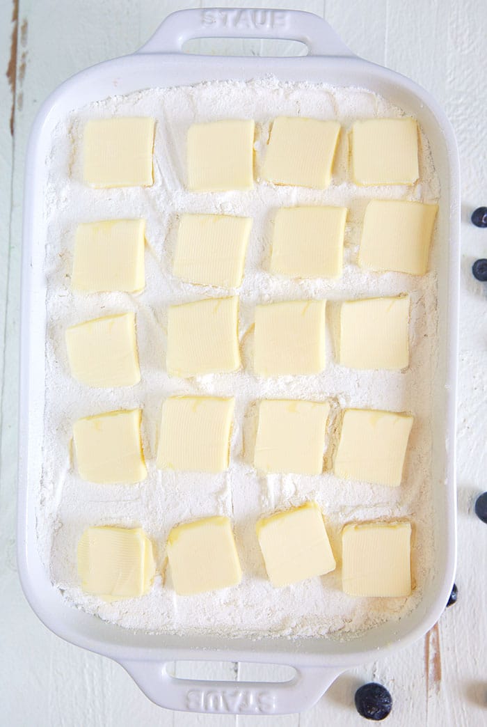 Cake mix and butter arranged in a baking dish for dump cake.