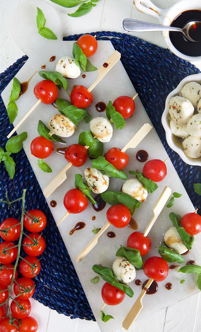 overhead shot of caprese skewers on a white marble board.