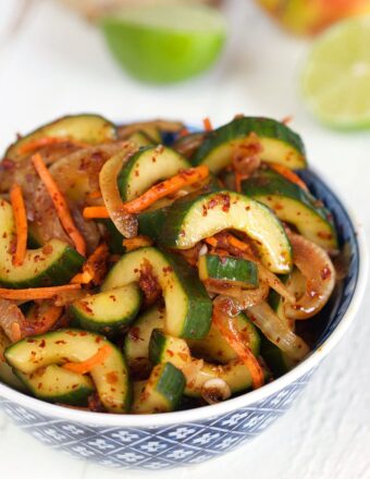 Cucumber Kimchi in a blue and white bowl on a white background.