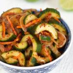 Cucumber Kimchi in a blue and white bowl on a white background.